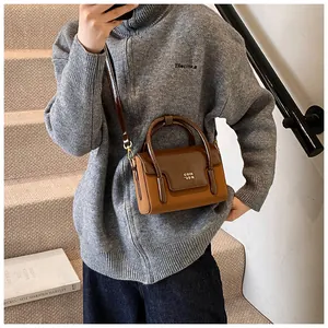 Detail of vintage square crossbody bag showing contrasting brown leather and metal logo
