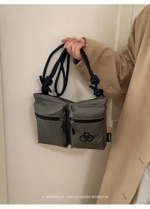 Detail of grey nylon crossbody bag with multi-pocket design and thick rope strap