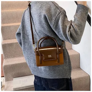 Brown dual-texture crossbody square bag shown on model with adjustable strap and handles