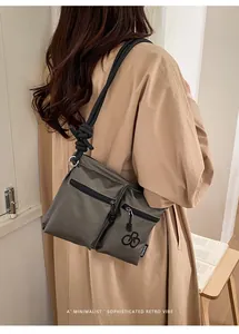 Detail of grey waterproof nylon crossbody bag featuring double zippers and knot strap