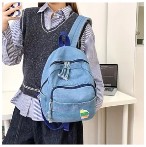 Détail d'un mini sac à dos en denim bleu clair avec rayures colorées et bords effilochés