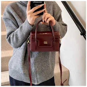Mirror selfie showing a burgundy square crossbody bag with gold hardware logo