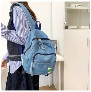 Détail du mini sac à dos en denim bleu délavé avec écusson arc-en-ciel brodé