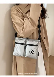Detail of silver metallic tote bag with front zipper pockets and black cord shoulder strap