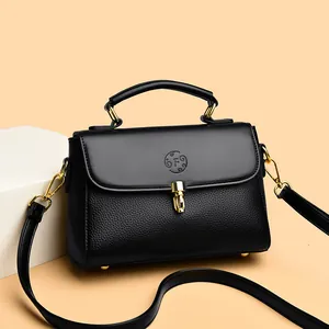 Classic black leather doctor bag with gold lock and top handle on a minimalist stand