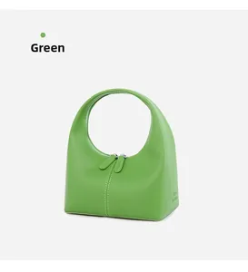 Dettaglio della borsa a mezzaluna in pelle verde con cuciture e doppia zip di chiusura