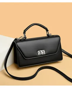 Detail view of the silver metal swivel lock on a black matte leather crossbody bag