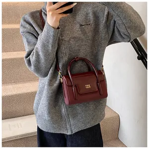 Detail shot of vintage burgundy square bag with glossy patent leather and gold logo
