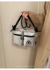 Detail of silver nylon crossbody bag featuring double front pockets and knotted handles