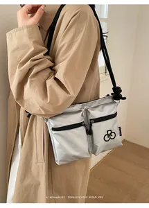 Macro view of silver tote bag showing glossy texture and dual zip pockets with rope strap