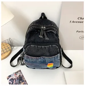 Détail du mini sac à dos en jean délavé avec broderie arc-en-ciel et design bicolore