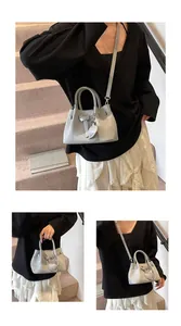 Close-up of light gray woven texture bag featuring a heart charm and metal clasp