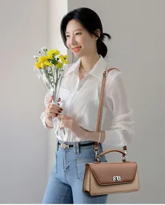 Detail of two-tone baguette bag with silver metal buckle and elegant top handle