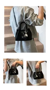 Detailed views of a black woven texture handbag with a heart charm and crossbody strap