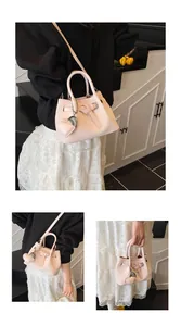 Close-up of light pink woven bucket bag featuring heart charm and detachable strap