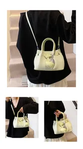 Detail of mint green woven handbag showing textured PU leather and heart pendant