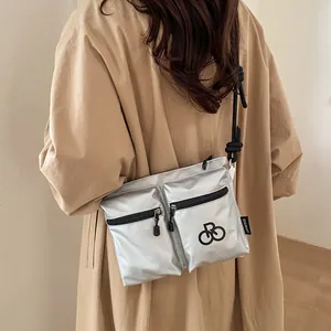Waterproof silver nylon crossbody bag with dual zipper pockets and braided rope strap