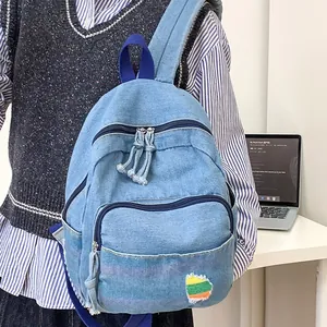 Mini sac à dos en jean bleu clair pour femme avec écusson décoratif et fermeture à pompon