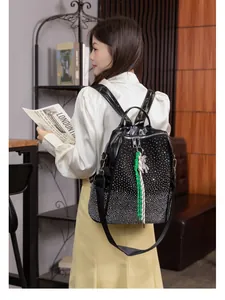 Sac à dos en cuir noir avec strass argentés et breloque ours porté par un mannequin