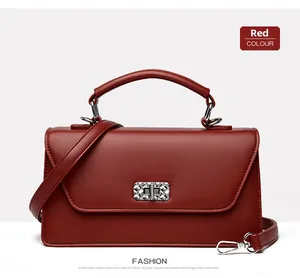 Detalle de bolso cuadrado rojo con cierre giratorio de metal plateado y cuero mate fino