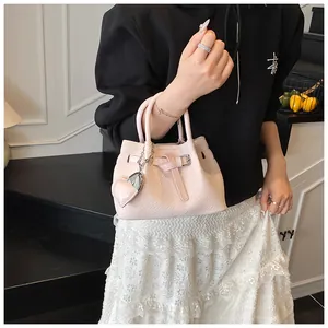 Detail of pink woven texture handbag featuring a heart charm and silver hardware accents