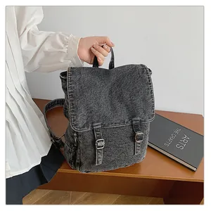 Vista detallada de la mochila de mezclilla lavada con hebillas metálicas y textura gris