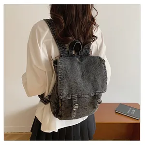 Vista lateral de mochila denim negra lavada con bolsillo metálico y correas retro
