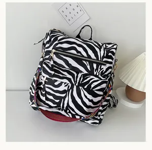 Detail of zebra pattern backpack featuring colorful woven strap and gold hardware accents