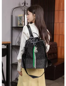 Détail d'un sac à dos noir à strass avec pendentif ours et breloque tissée sur le zip