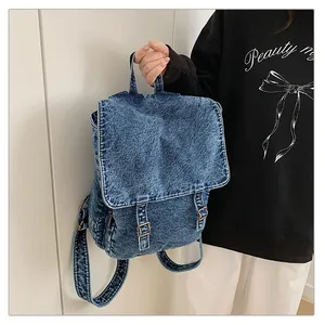 Detalle de la mochila de mezclilla lavada azul con cierre de solapa y hebillas metálicas