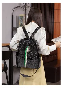 Détail d'un sac à dos noir à strass avec pendentif ours porté par un mannequin