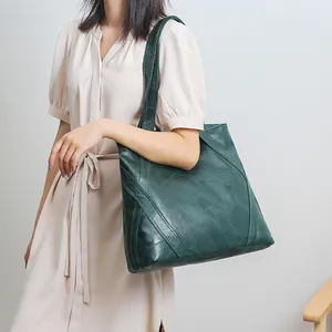 Detail of dark green geometric patchwork tote bag with double shoulder straps shown on model