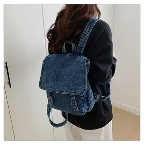 Vista detallada de mochila denim lavada con correas ajustables y hebillas metálicas retro