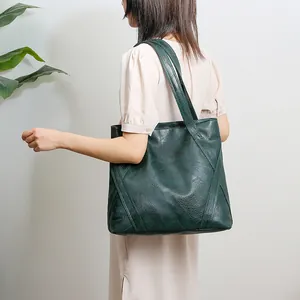 Macro detail of dark green paneled leather tote bag with grainy texture and stitching