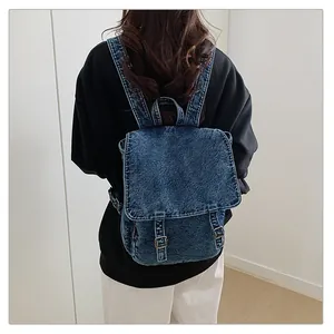 Vista trasera de una mochila vintage de mezclilla lavada sobre una sudadera con capucha negra