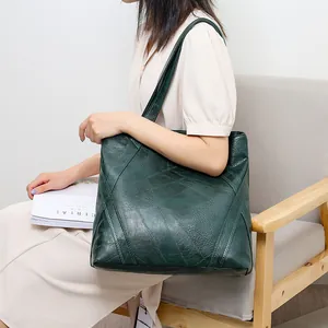 Detail view of dark green patchwork tote bag with lychee texture on a neutral background