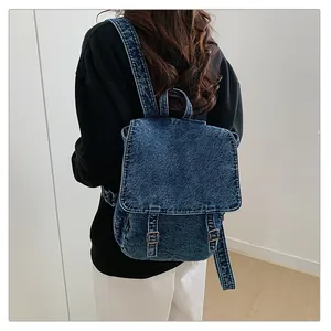 Detalle de mochila de tela vaquera lavada con hebillas de cuero y textura retro