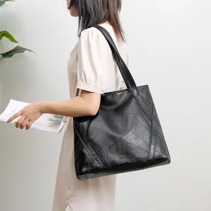 Close-up of black patchwork tote bag with vintage texture shown on female model
