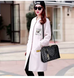 Quilted black handbag with golden hardware and butterfly pendant on a pink wool coat