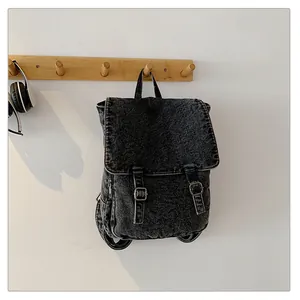 Detalle de mochila de mezclilla lavada vintage con correas de cuero y cremallera lateral
