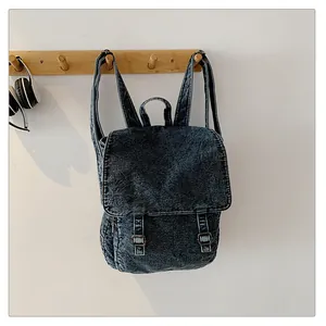 Detalle de mochila de tela vaquera lavada vintage con hebillas metálicas y solapa imán