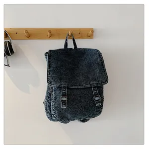 Detalle de la mochila de mezclilla lavada con hebillas metálicas dobles y asa