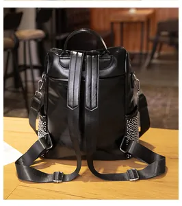 Vue arrière détaillée d'un sac à dos décontracté en cuir noir avec bretelles sur table en bois