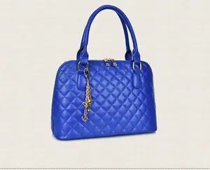 Detail of royal blue quilted handbag with golden butterfly charm and diamond stitching