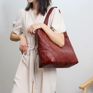 Close-up of geometric patchwork stitching on brown leather tote bag for women