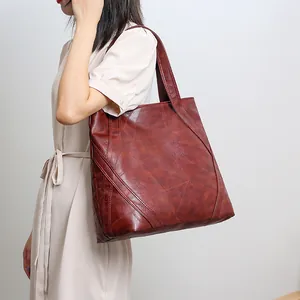 Detail of a large brown vintage tote bag with irregular geometric stitching on the leather