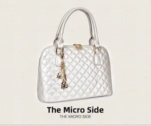 Detail of pearl white shell tote bag with diamond quilted stitching and golden butterfly charm