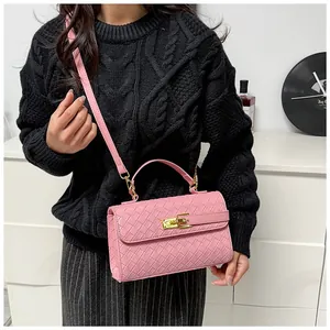 Dettaglio borsa intrecciata rosa con chiusura a rotazione dorata su sfondo maglione nero