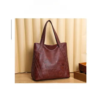 Detailed view of dark brown washed leather tote with irregular stitching and dual straps