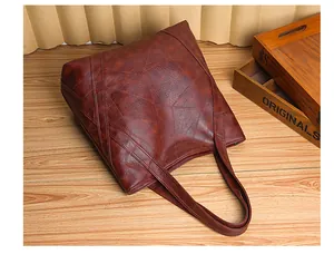 Detail of dark brown leather tote bag with unique geometric stitching on wooden table